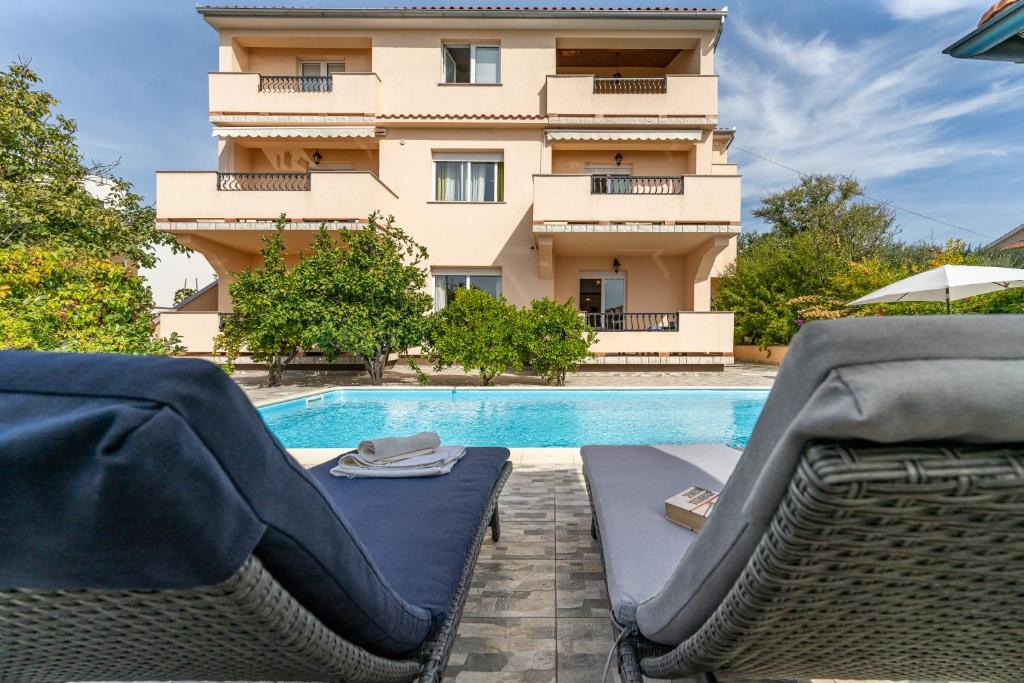 a swimming pool with two lounge chairs and a building at JURIĆ Apartments-Rab in Rab
