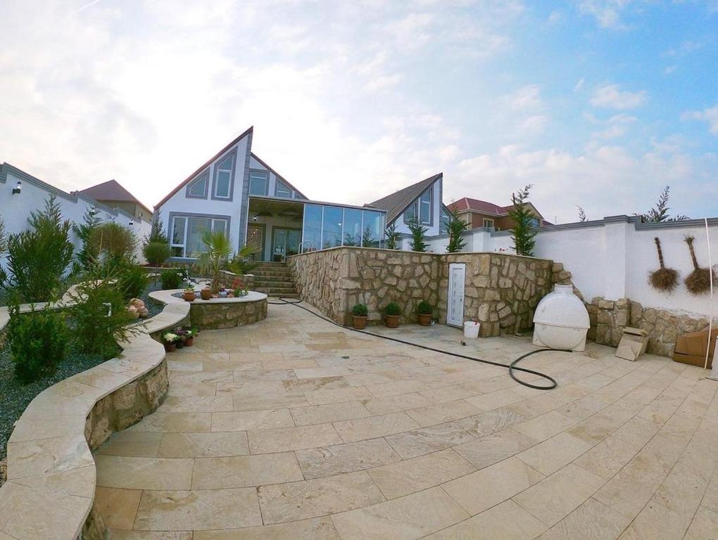 uma casa com um pátio de pedra e uma cerca em Caspian Villa Merdekan em Şüvǝlǝn