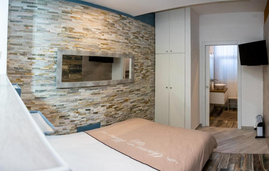 een slaapkamer met een bakstenen muur en een tv bij Catalani Charme Apartament in Cagliari