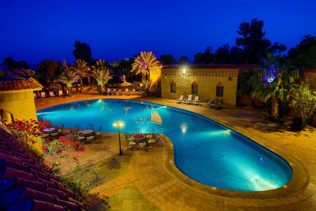 a large swimming pool in a yard at night at Palm's Hotel Club in Erfoud