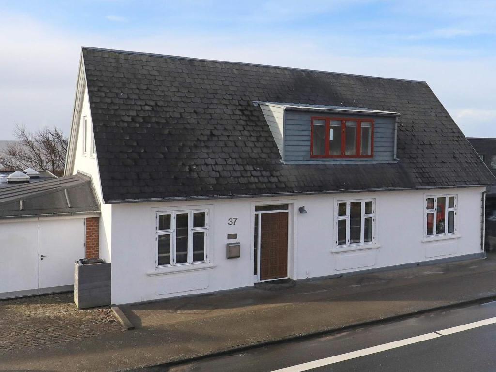 a white house with a black roof on a street at Holiday home Esbjerg V XX in Esbjerg