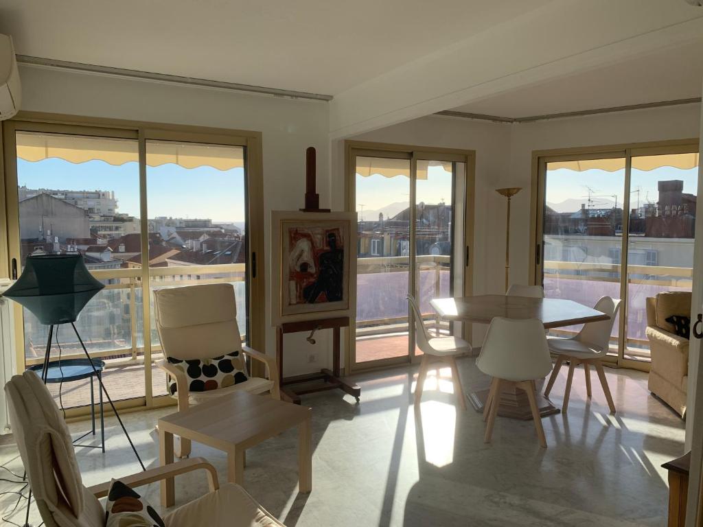 un salon avec une table, des chaises et des fenêtres dans l'établissement Le République, à Cannes