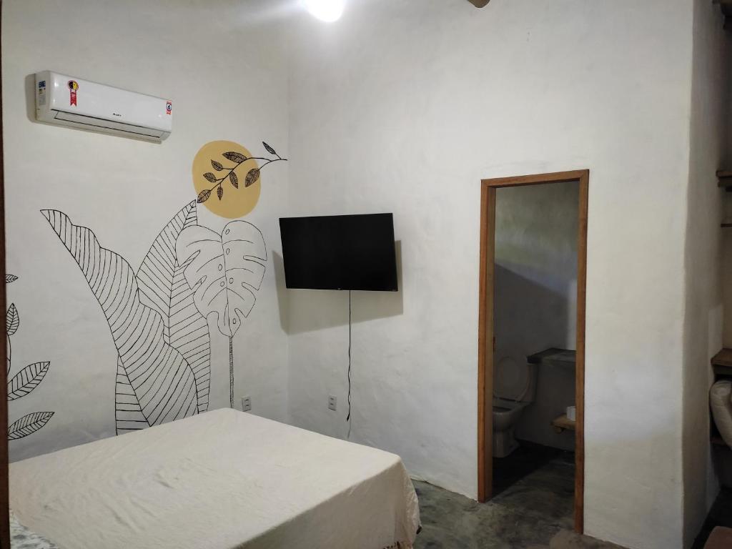 a room with a bed and a tv on a wall at Recanto da Alice in Trancoso
