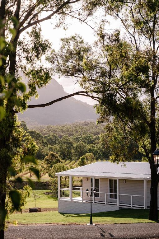 a white house with a mountain in the background at Leogate Estate Villas in Pokolbin