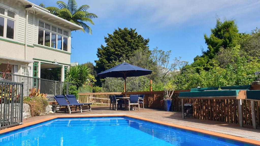 a swimming pool with a table and an umbrella at Bluff Hill Bed & Breakfast in Napier