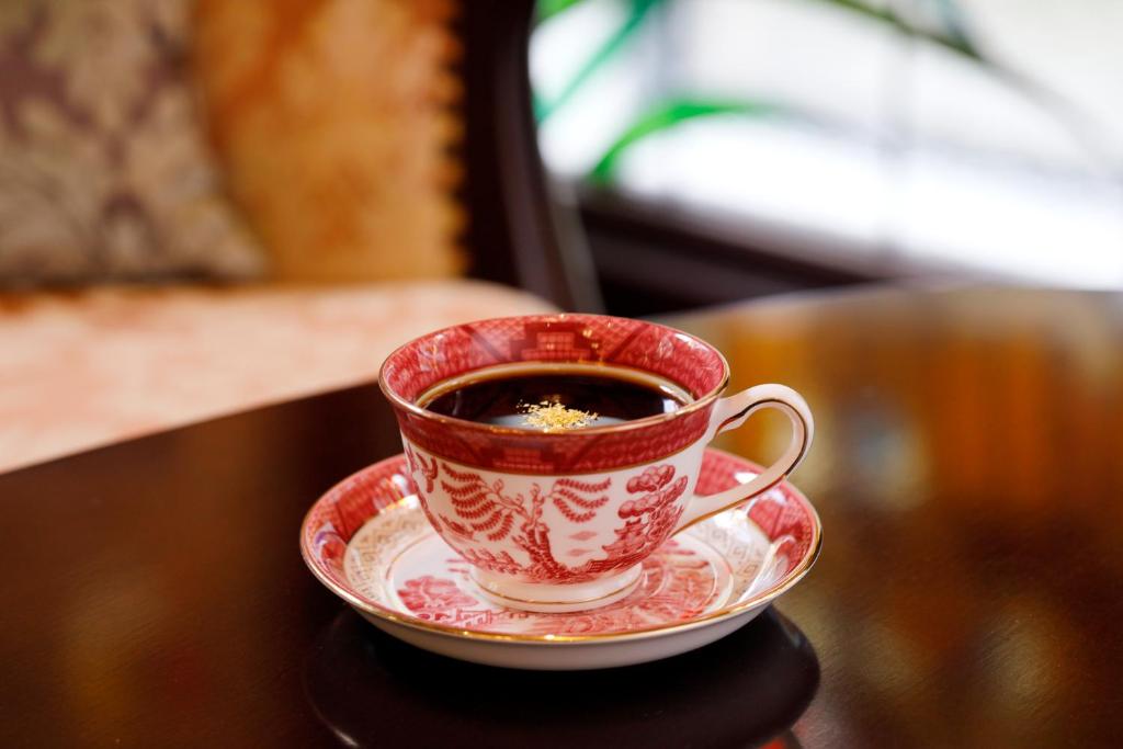 a red and white cup of coffee on a table at Kanazawa Hakuchoro Hotel Sanraku -Natural Hot Spring- in Kanazawa