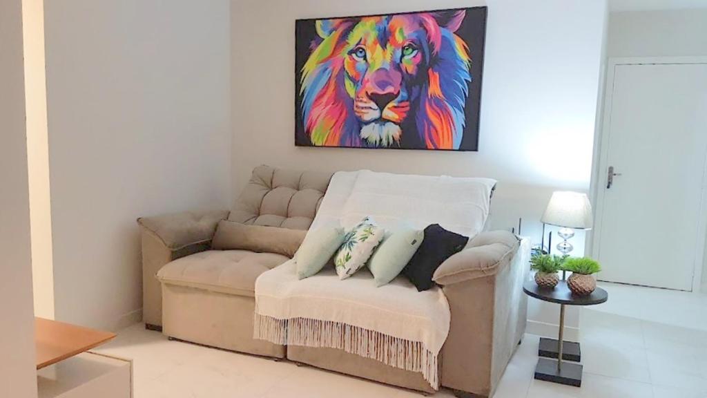 a couch in a living room with a painting of a lion at Apartamento CONFORTO prox do SHOPPING NAÇÕES prox ABBA Church - cozinha completa - Ar condicionado - WiFi - Smart Tv 32' - Youtube e Apps - estacionamento privado - Portaria 24h - Acomoda até 8 pessoas - Anfitriã SuperHost no BNB 5 Estrelas in Criciúma