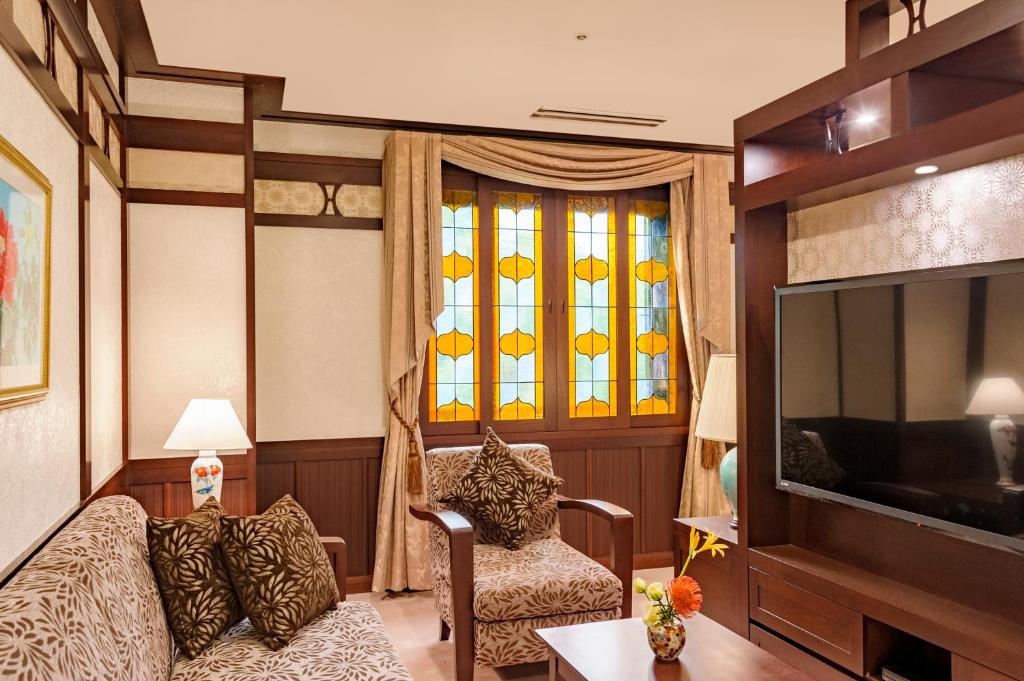 a living room with a couch and a tv at Kanazawa Hakuchoro Hotel Sanraku -Natural Hot Spring- in Kanazawa