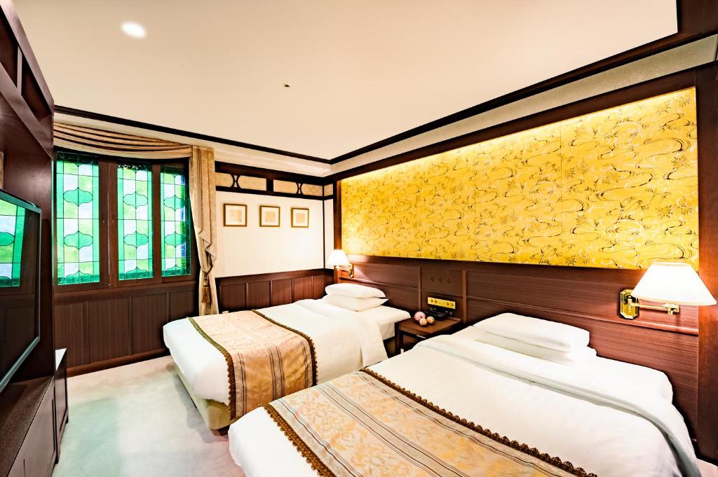 a room with three beds and a yellow wall at Kanazawa Hakuchoro Hotel Sanraku -Natural Hot Spring- in Kanazawa