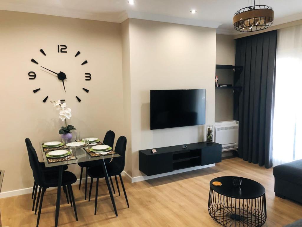 a living room with a table and a clock on the wall at Rooftop Sunset View Apartment in Tirana