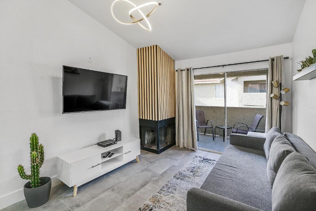 a living room with a couch and a tv on a wall at Condo close to Strip and Raiders Stadium in Las Vegas