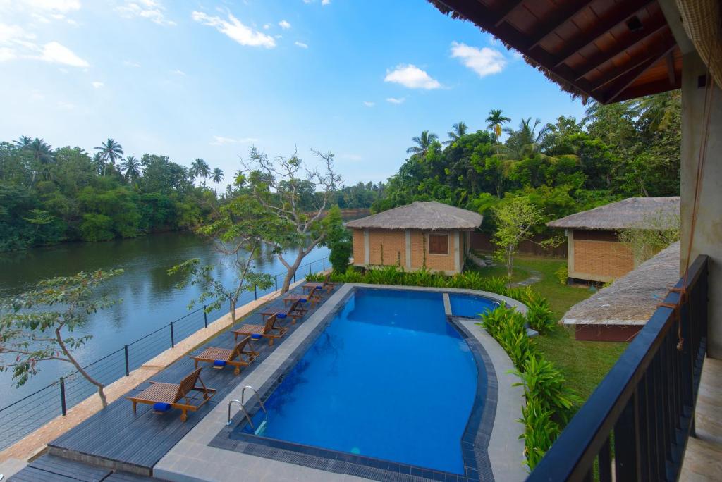 uitzicht op het zwembad en de rivier vanaf het balkon van een resort bij Karunakarala Ayurveda Resort in Wayikkal