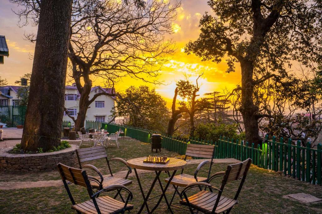 a table and chairs with a sunset in the background at StayVista at Nau Nabh Cottage - Paradisiacal Abode in Shimla