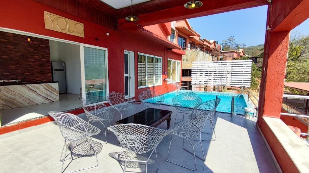 a patio with chairs and a table and a swimming pool at Villa 408-Dr Wade in Royal Palms Mumbai in Mumbai