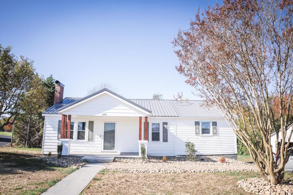 a white house with a tree in front of it at Modern Cottage Near Hospitals and Brewery! in Morganton