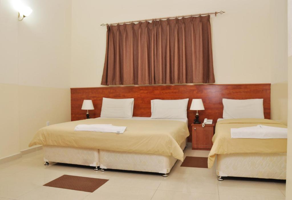 a bedroom with two beds and a window at Africana Hotel in Dubai