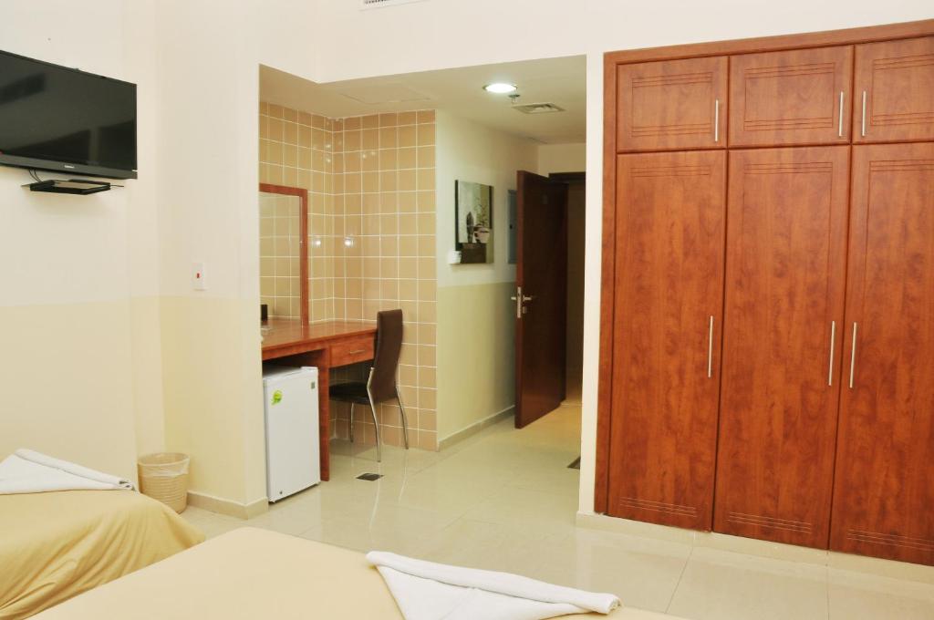 a bedroom with a bed and a desk and a television at Africana Hotel in Dubai