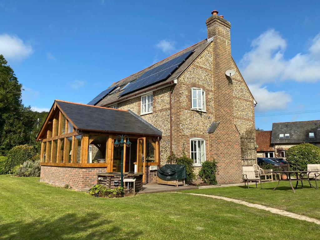 a large brick house with a conservatory on a lawn at Eco-friendly Dorset cottage with spa set in heart of countryside in Sydling St Nicholas