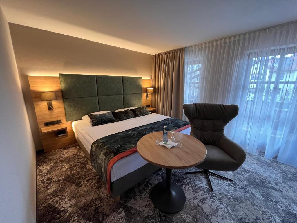 ein Hotelzimmer mit einem Bett, einem Tisch und einem Stuhl in der Unterkunft Appartment-Hotel-Hölzl in Grünwald