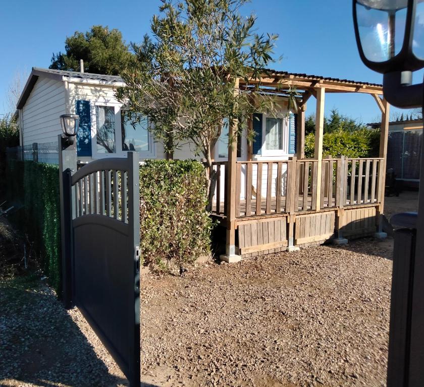 une clôture avec un portail en face d'une maison dans l'établissement Mobile home Portiragnes, à Portiragnes
