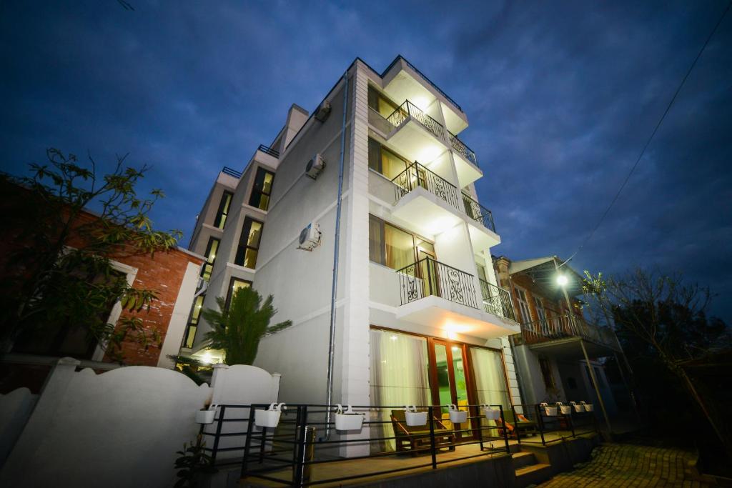 a tall white building with a lot of windows at night at Lemon in Kutaisi