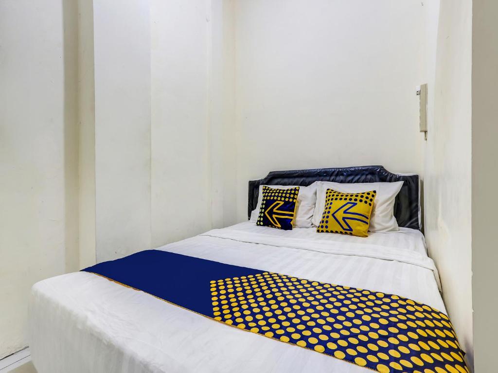 a bed with yellow and blue pillows on it at SPOT ON 90780 Gang Tengah Homestay Syariah in Semarang