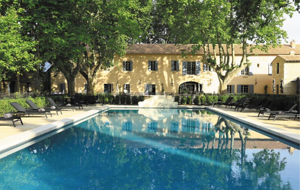 une piscine avec une fontaine en face d'un bâtiment dans l'établissement Domaine De Manville, aux Baux-de-Provence