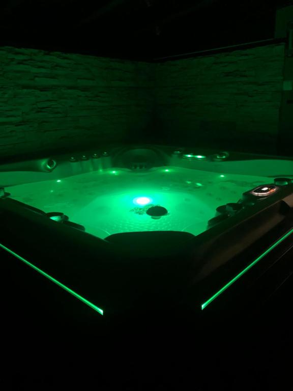 bañera de hidromasaje con agua verde en una habitación oscura en Zengő Kincse SPA Vendégház Hosszúhetény, en Hosszúhétény-Szőlőhegy