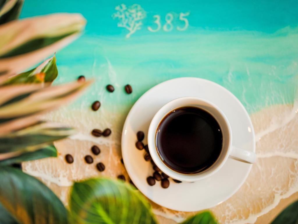 a cup of coffee on a plate with coffee beans at Hotel 385 in Miyako Island