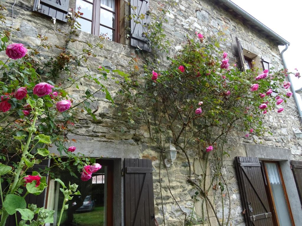ein Steingebäude mit rosa Rosen, die darauf wachsen in der Unterkunft Gîte au coeur de la Bretagne in Roudouallec
