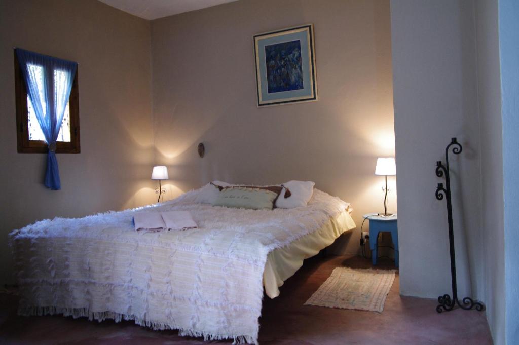 ein Schlafzimmer mit einem weißen Bett und zwei Lampen in der Unterkunft Au Bord de l'Eau in Setti Fatma
