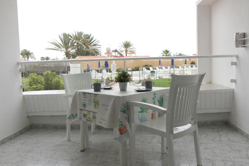 Estancia en Complejo Tamarán - Playa del Inglés في بلايا ديل إنغلز: طاولة بيضاء وكراسي على شرفة مطلة