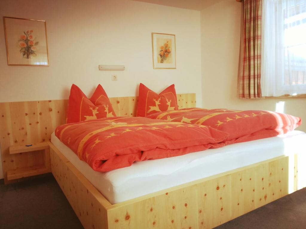 a bedroom with a wooden bed with red sheets at Ferienhaus Laimerbauer in Faistenau
