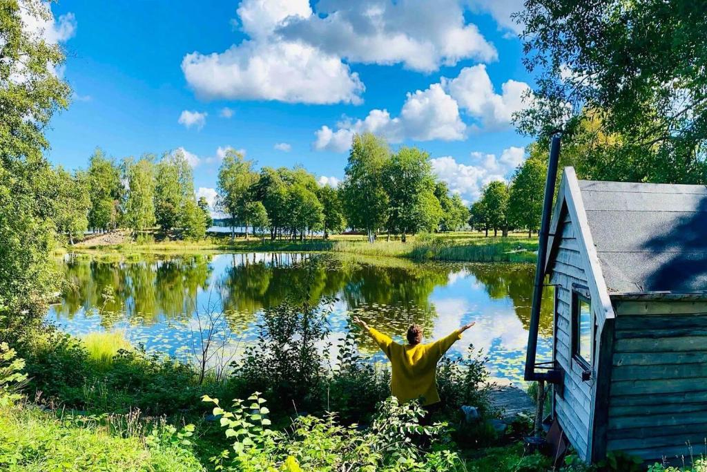 a man standing in front of a lake with his arms out at Romantic Cabin right on the lake with fire place in Stjärnsund