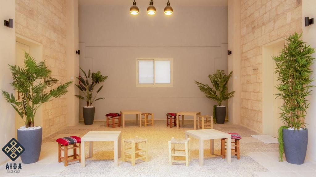 Aida Guest house في الناصرة: غرفة بها طاولات وكراسي ونباتات