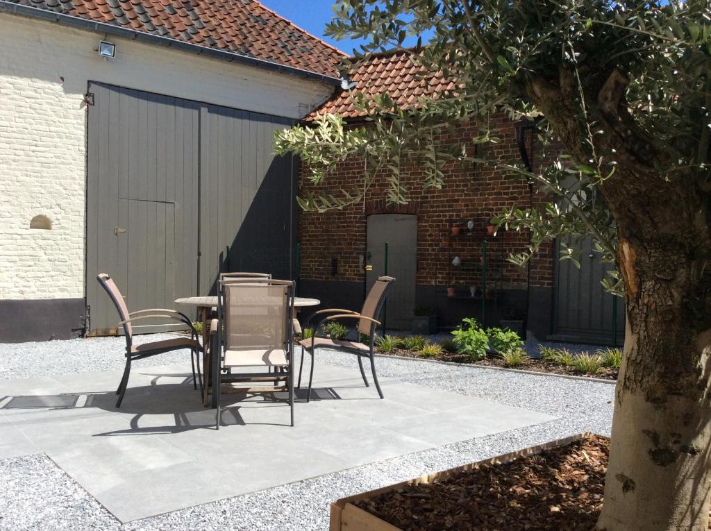 a patio with a table and chairs in front of a building at DE LANDSHOEVE vakantiewoningen in Zwalm