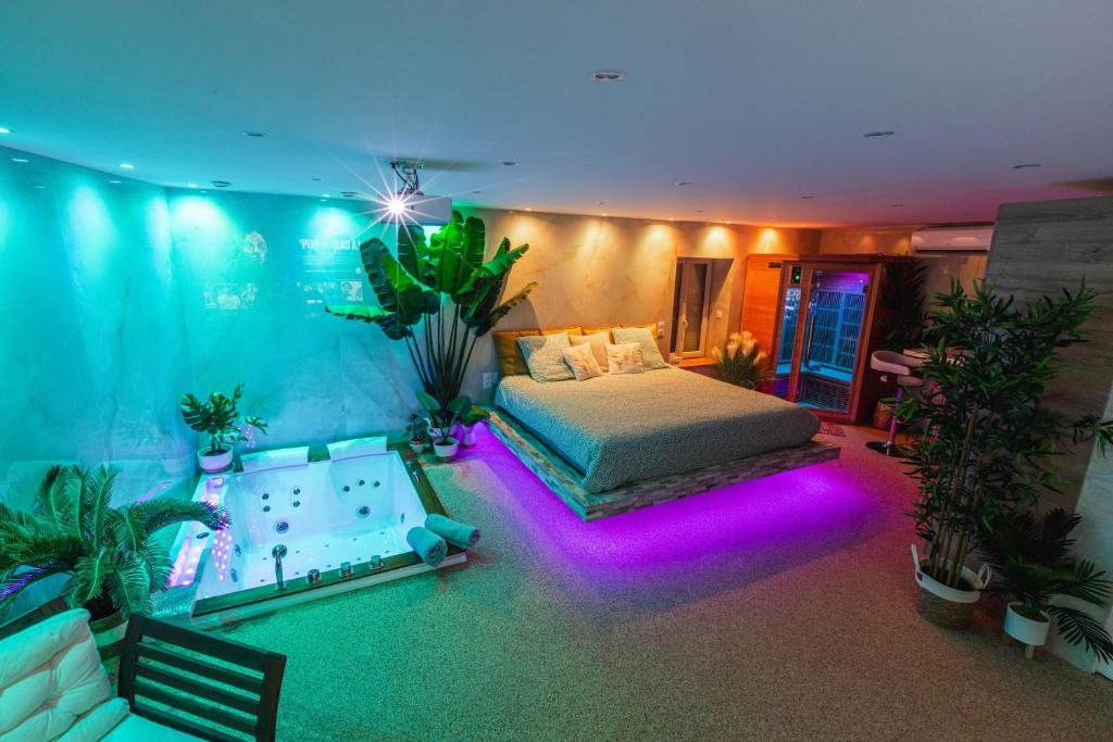 a bedroom with a bed and a tub with purple lights at La Suite d'Aubière in Aubière