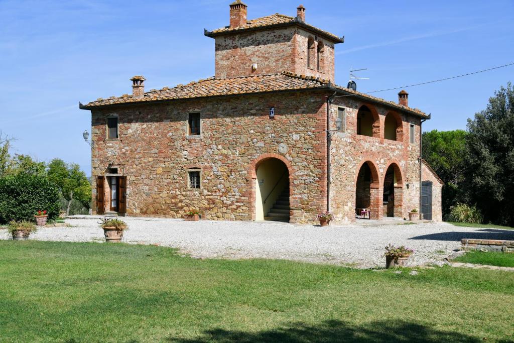 un gran edificio de ladrillo con una torre en la parte superior en Casale le Rondini by VacaVilla, en Lucignano