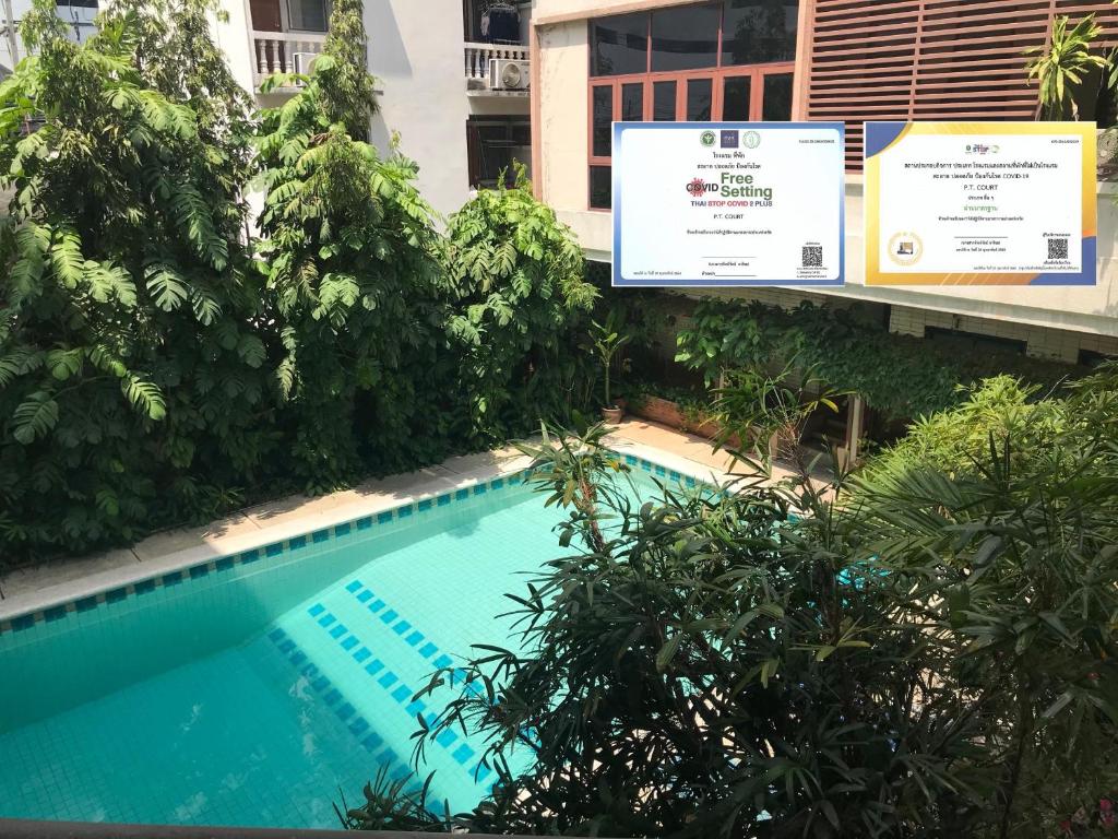 einem Pool vor einem Gebäude mit Bäumen in der Unterkunft P.T. Court in Bangkok