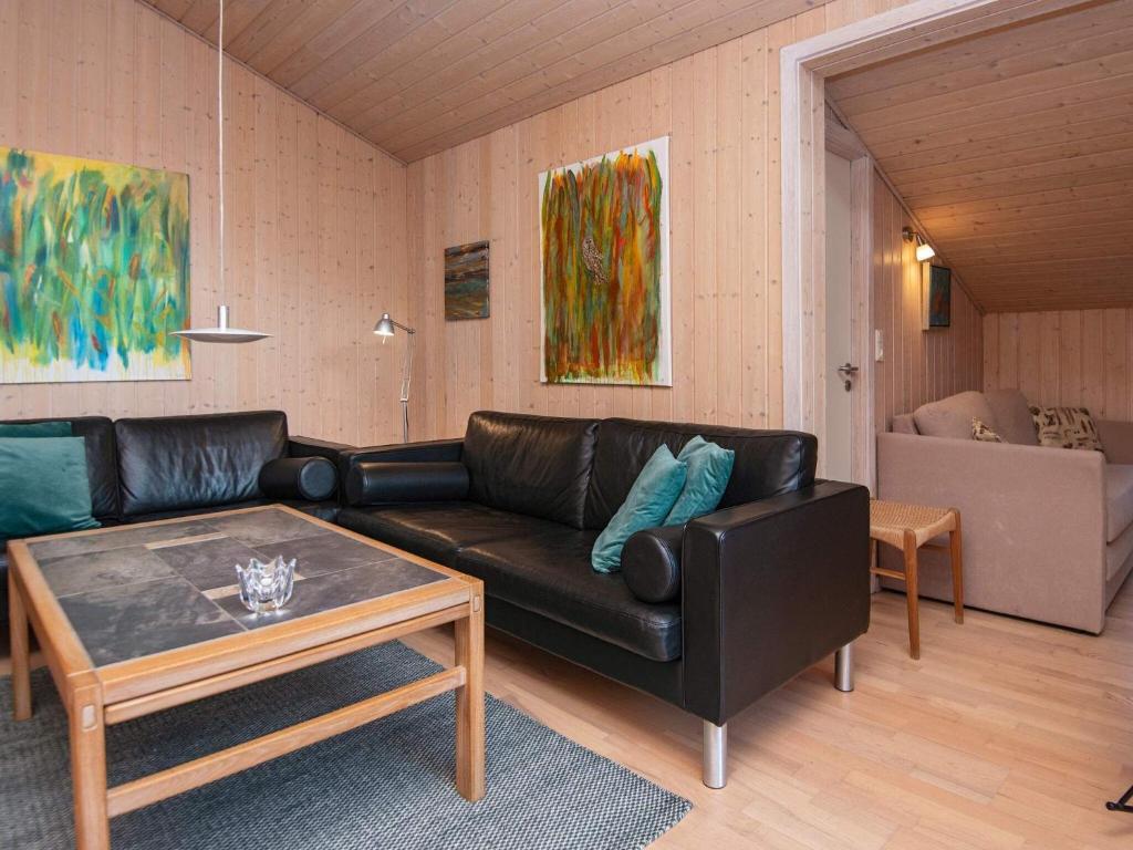ein Wohnzimmer mit einem schwarzen Ledersofa und einem Tisch in der Unterkunft Holiday home Ebeltoft CXLVIII in Ebeltoft