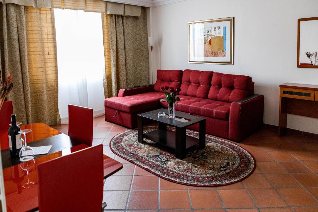 a living room with a red couch and a table at Hotel Pushkin in Uralsk