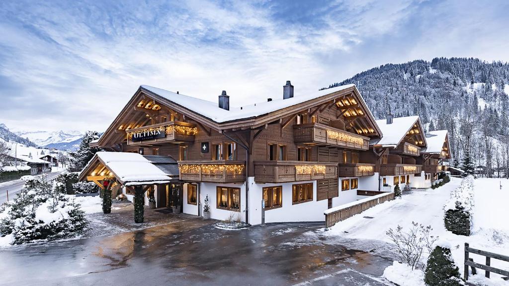 uma grande casa de madeira com neve no chão em Ultima Gstaad em Gstaad