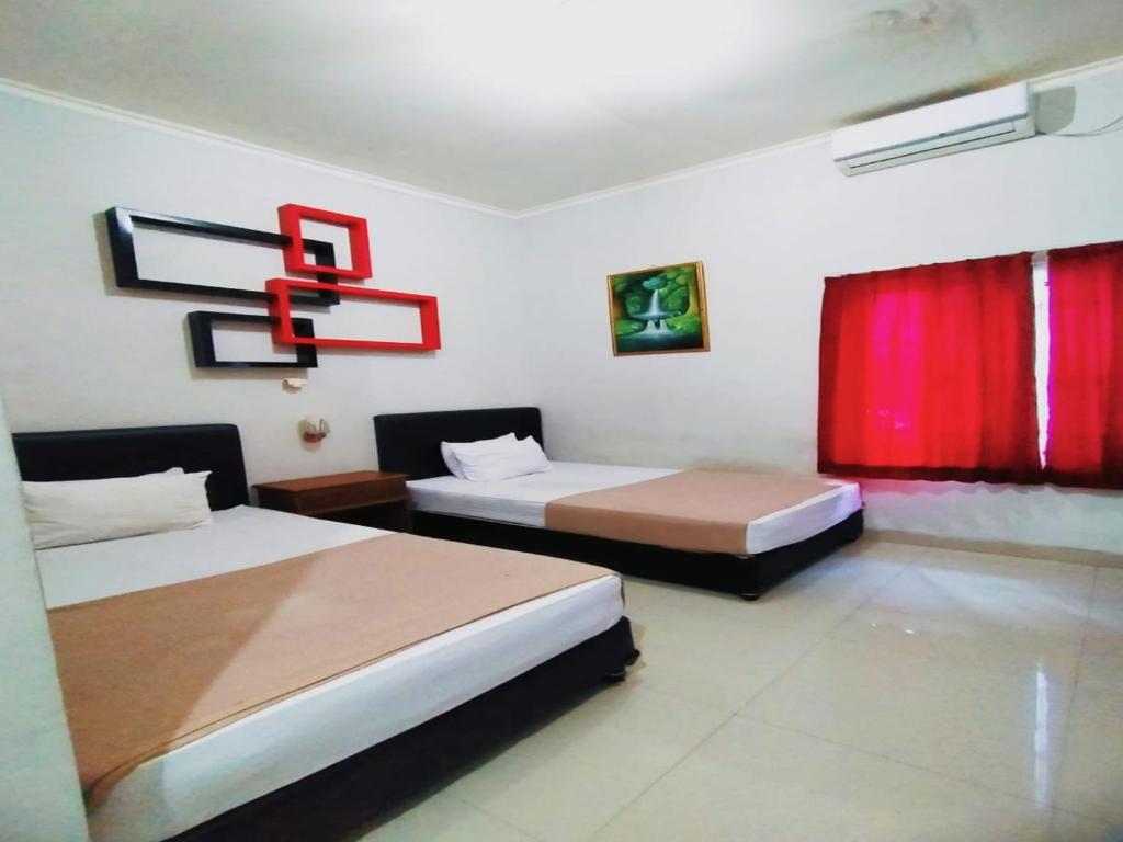 een slaapkamer met 2 bedden en een rood gordijn bij RedDoorz at Hotel Nuansa Ngawi in Ngawi