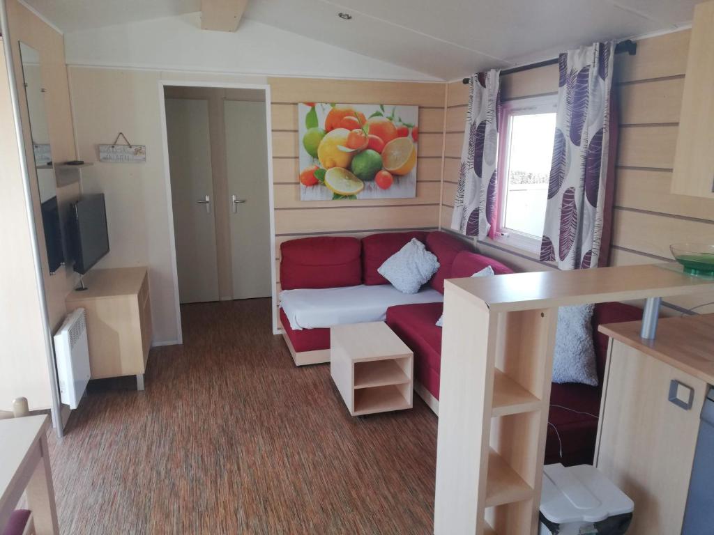 Habitación pequeña con sofá rojo y ventana en Grand Mobil home 3chbr 2sdb camping La Carabasse en Vias