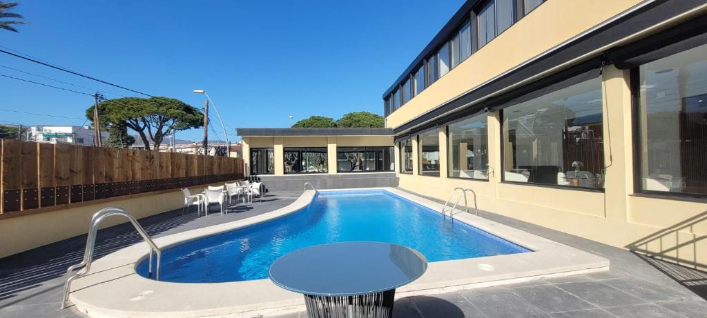 einen Pool mit einem Tisch neben einem Gebäude in der Unterkunft Hotel 153 in Castelldefels