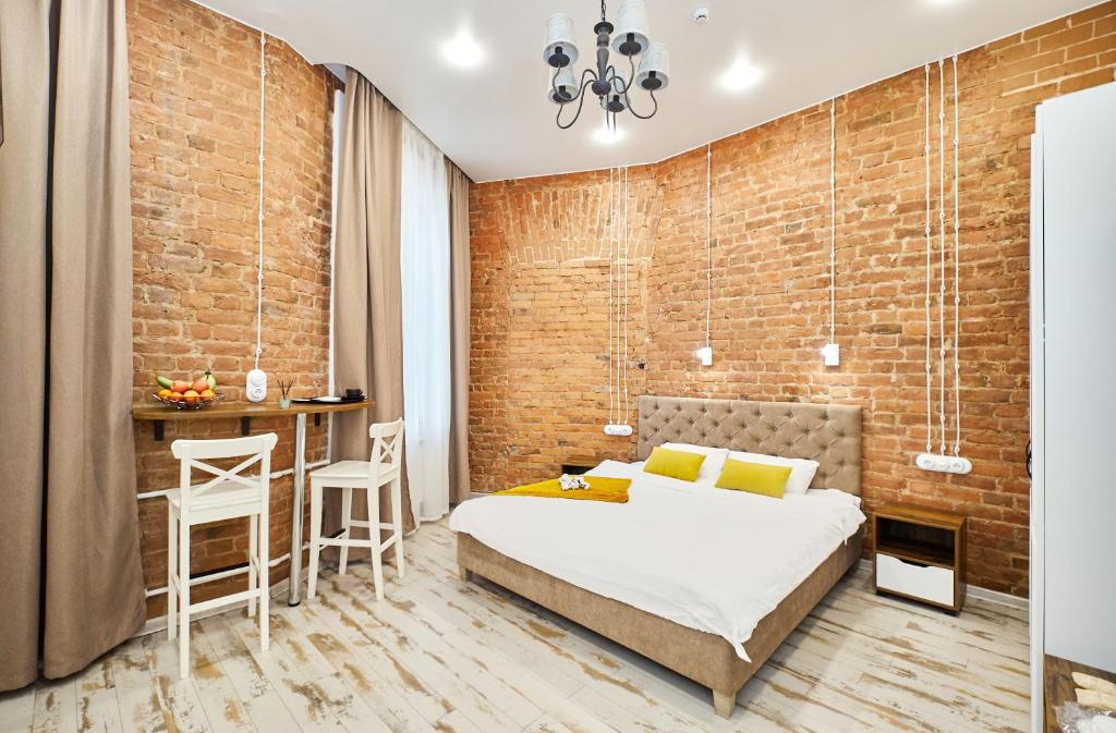 a bedroom with a brick wall and a bed and a table at GrandWhite Apart in Saint Petersburg
