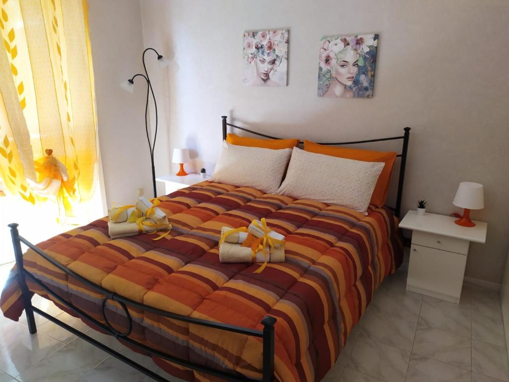 una camera da letto con un grande letto con lenzuola arancioni e arancioni di Vanedda monile (casa centro storico) a Modica