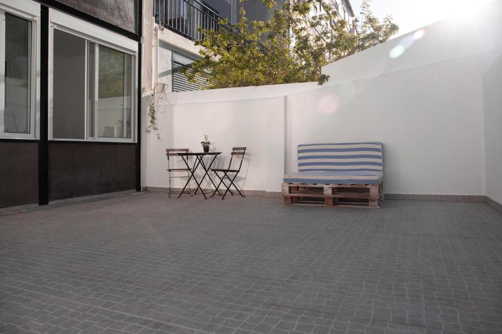 a patio with a chair and a table next to a white wall at Entrecampos - Family apartment with Terrace in Lisbon