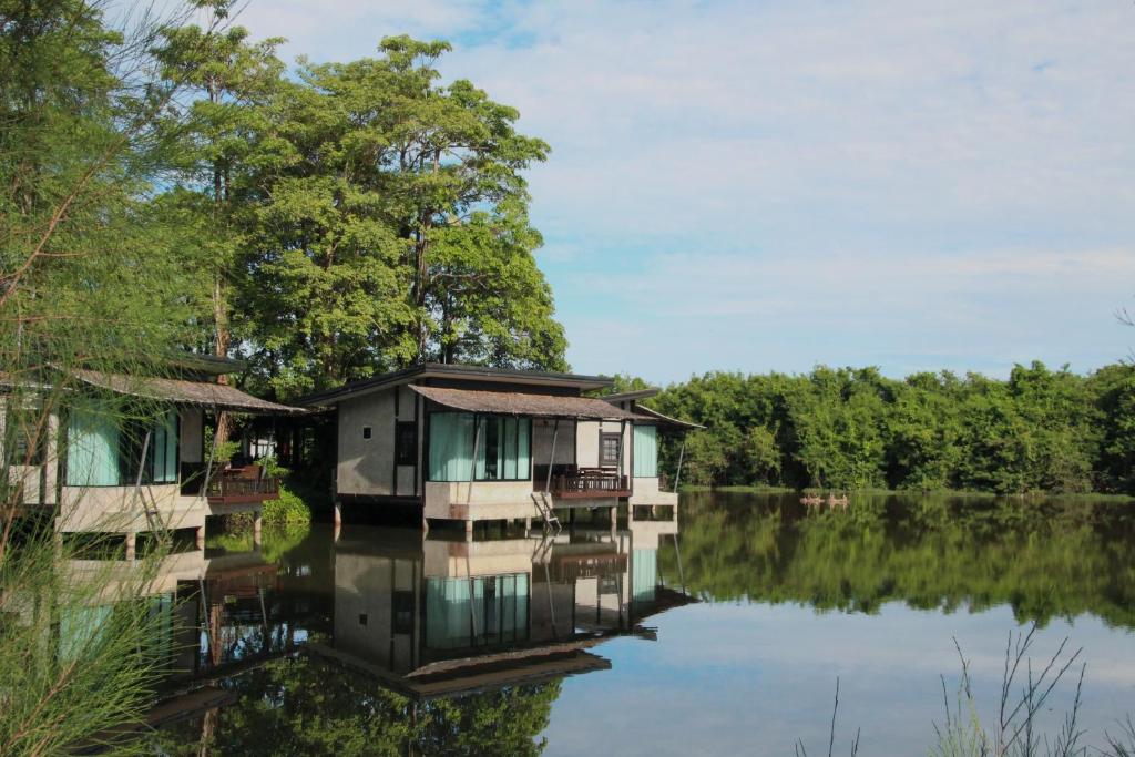 a house on a lake with its reflection in the water at Banpu Resort Trat in Trat