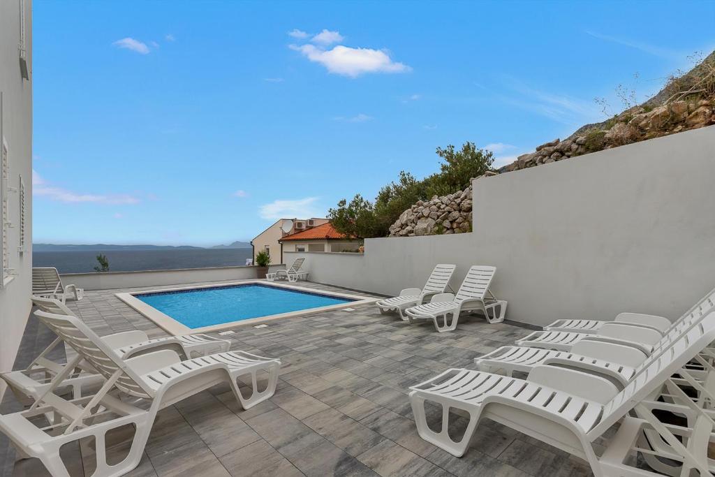 eine Terrasse mit Stühlen und einem Pool in der Unterkunft Vila Mila Mare in Drašnice